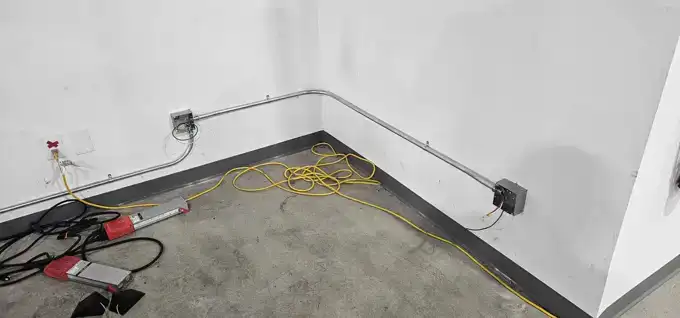 Charging receptacles and surface conduit along the bay wall.